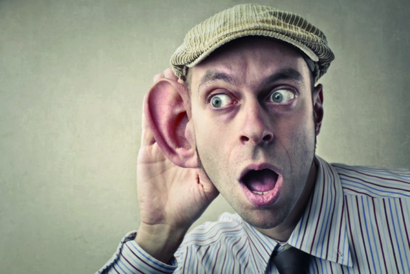 Un hombre escucha con una oreja enorme