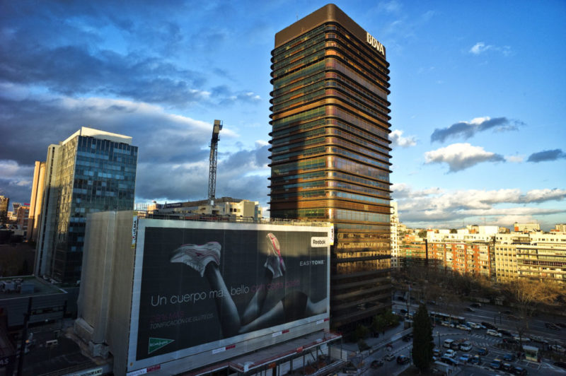 En la foto se ve un gran cartel al lado del edificio BBVA de la Gran Vía de Madrid